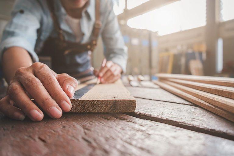 Carpenter working with equipment on wooden table in carpentry sh